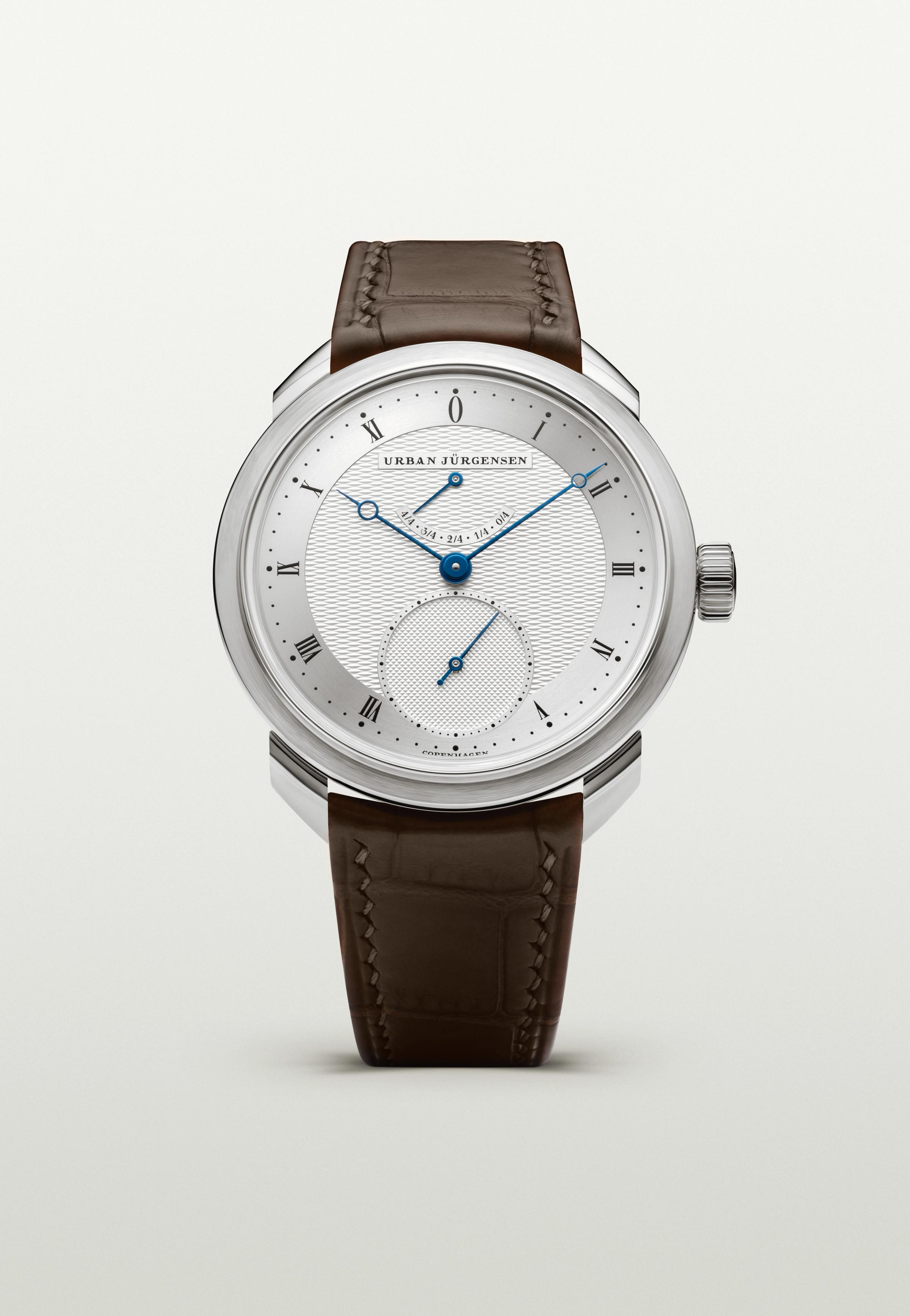 Platinum Urban Jürgensen watch with silver guilloché dial, blued hands, power reserve indicator, and brown leather strap.