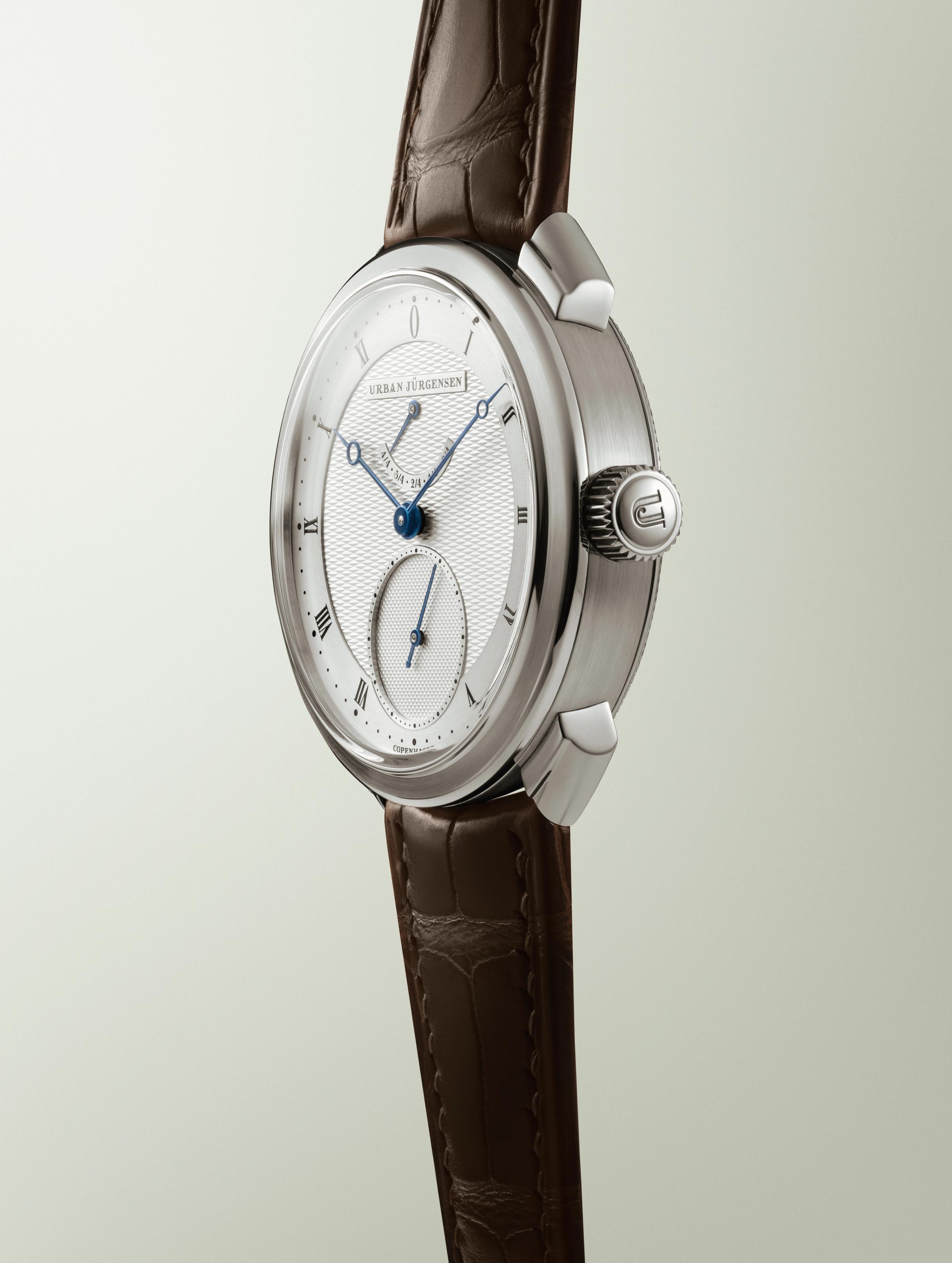 Urban Jürgensen wristwatch with guilloché dial, blue hands, Roman numerals, small seconds subdial, and power reserve indicator.