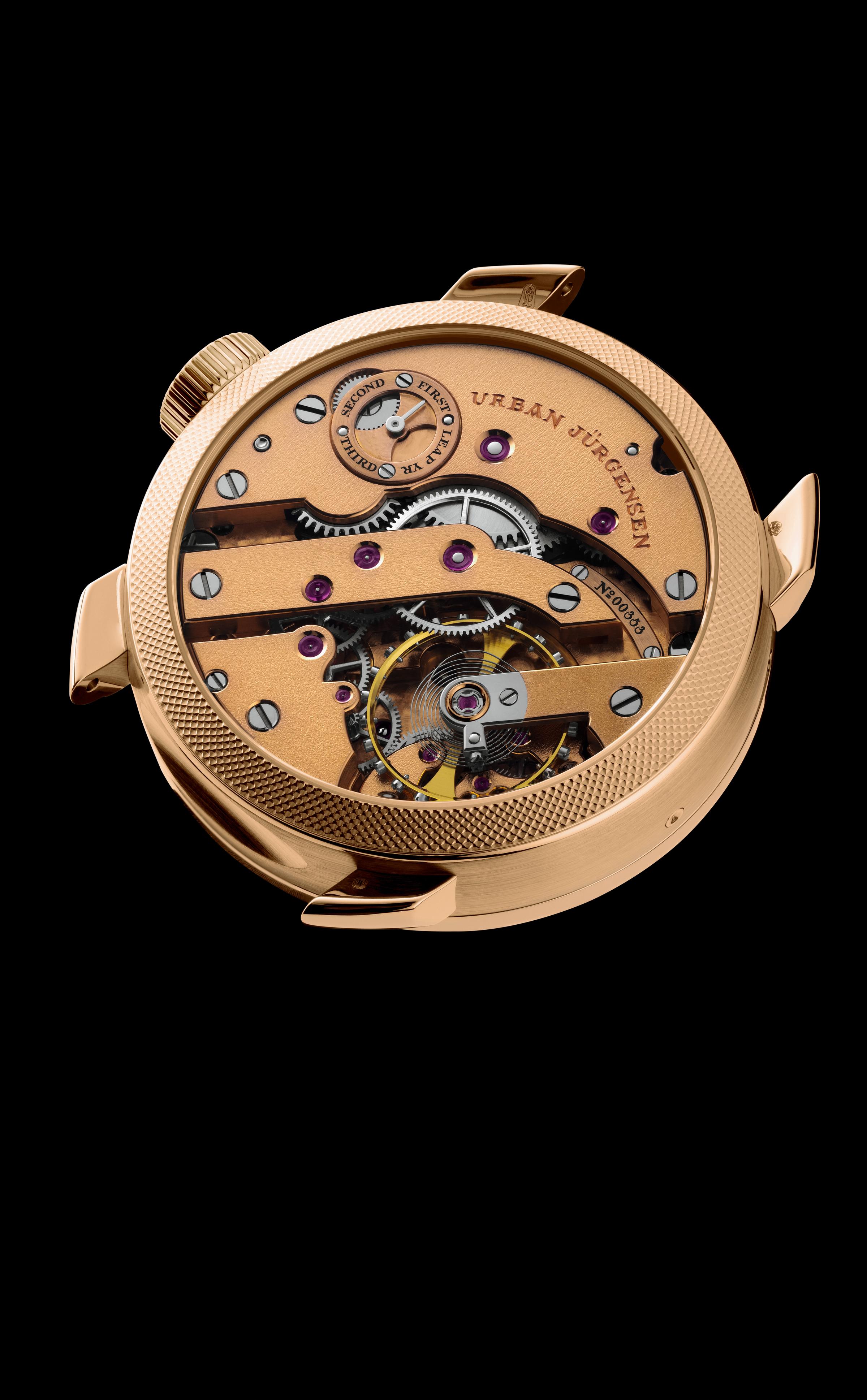 Reverse view of a rose gold Urban Jürgensen watch case showing the mechanical movement with engraved leap year indicator, ruby jewels, and visible tourbillon.