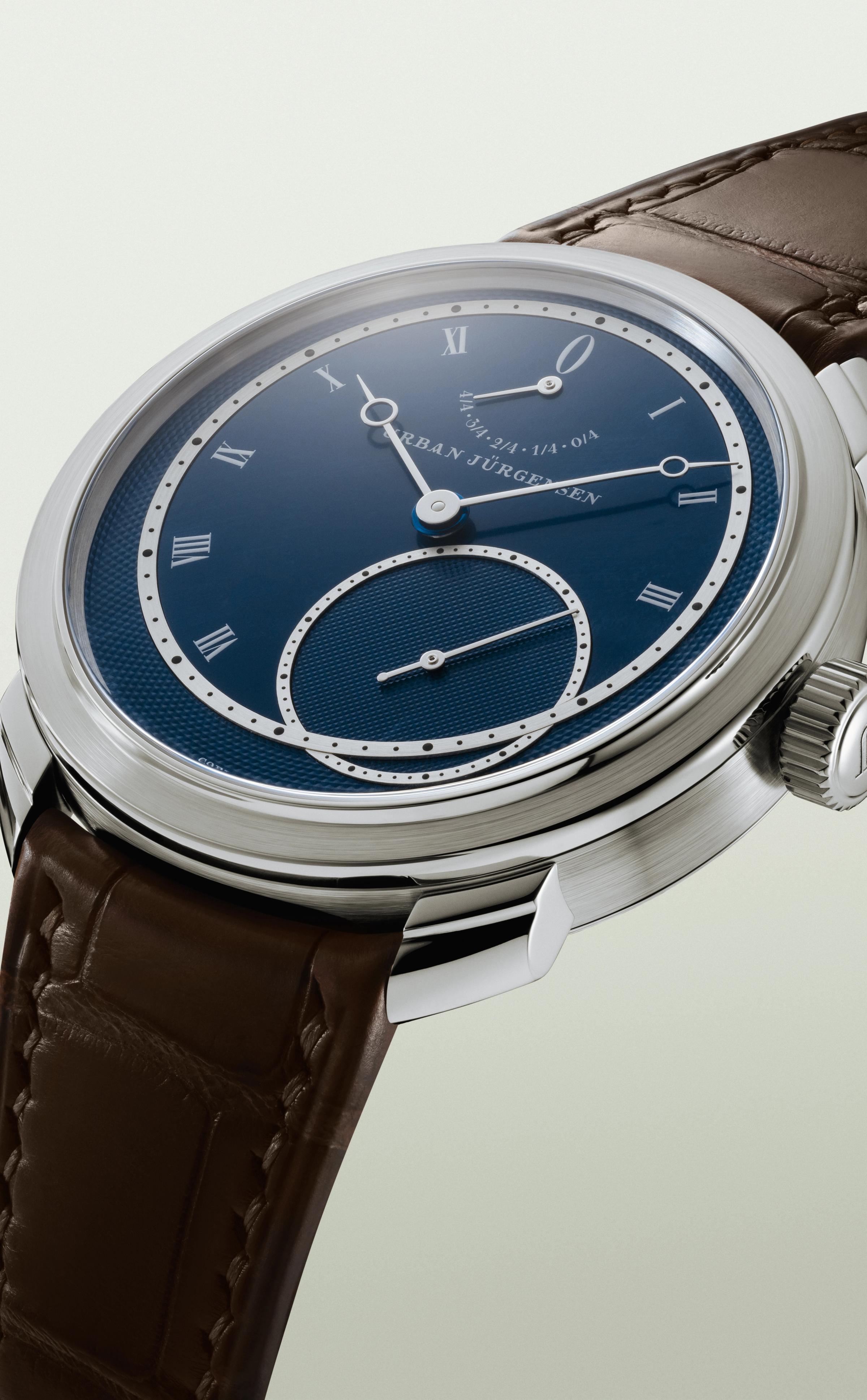 Platinum Urban Jürgensen wristwatch with blue guilloché dial, silver Roman numerals, power reserve indicator, and brown leather strap.