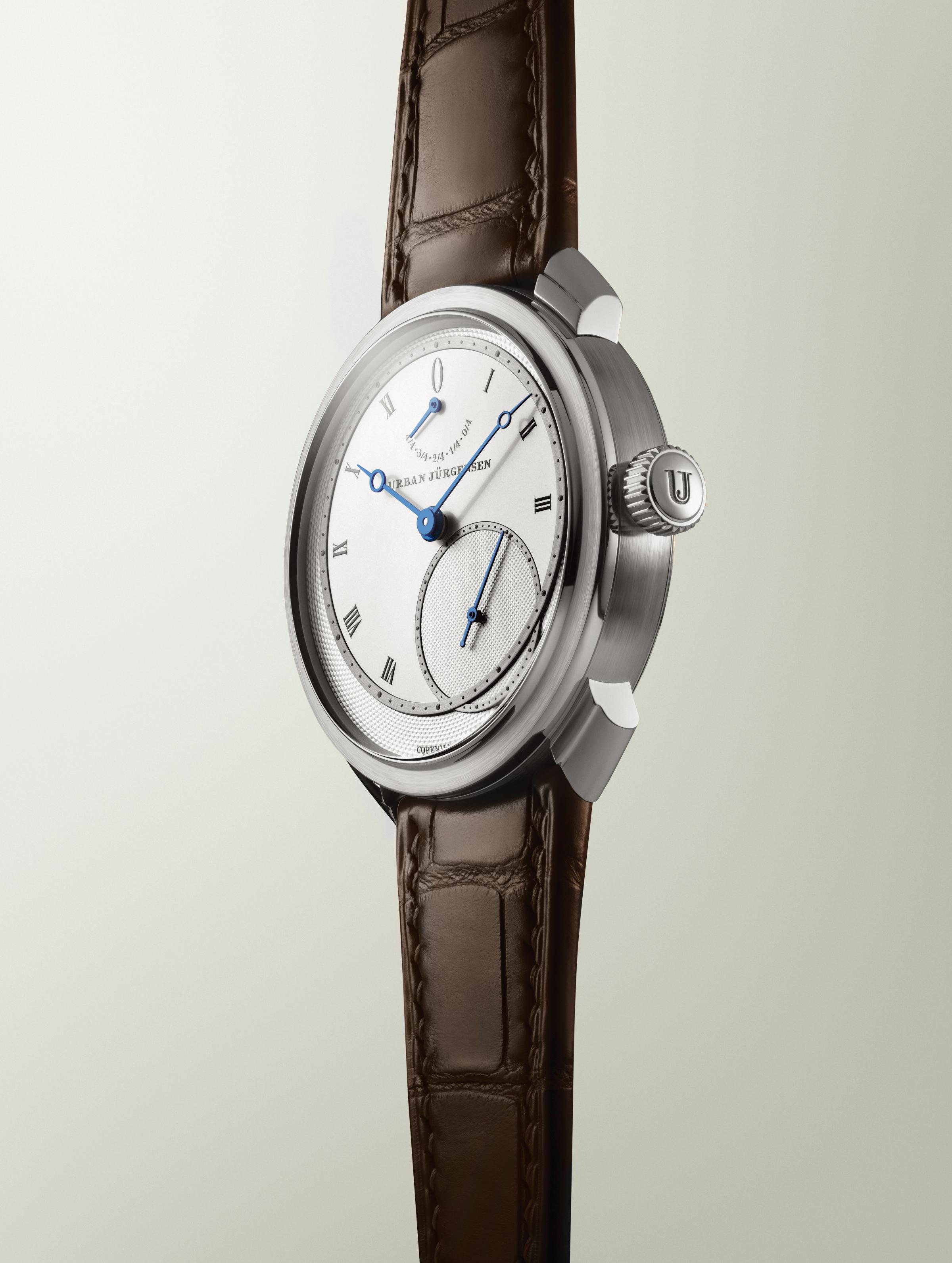 Platinum Urban Jürgensen wristwatch with silver dial, blued hands, Roman numerals, power reserve indicator, and brown leather strap.