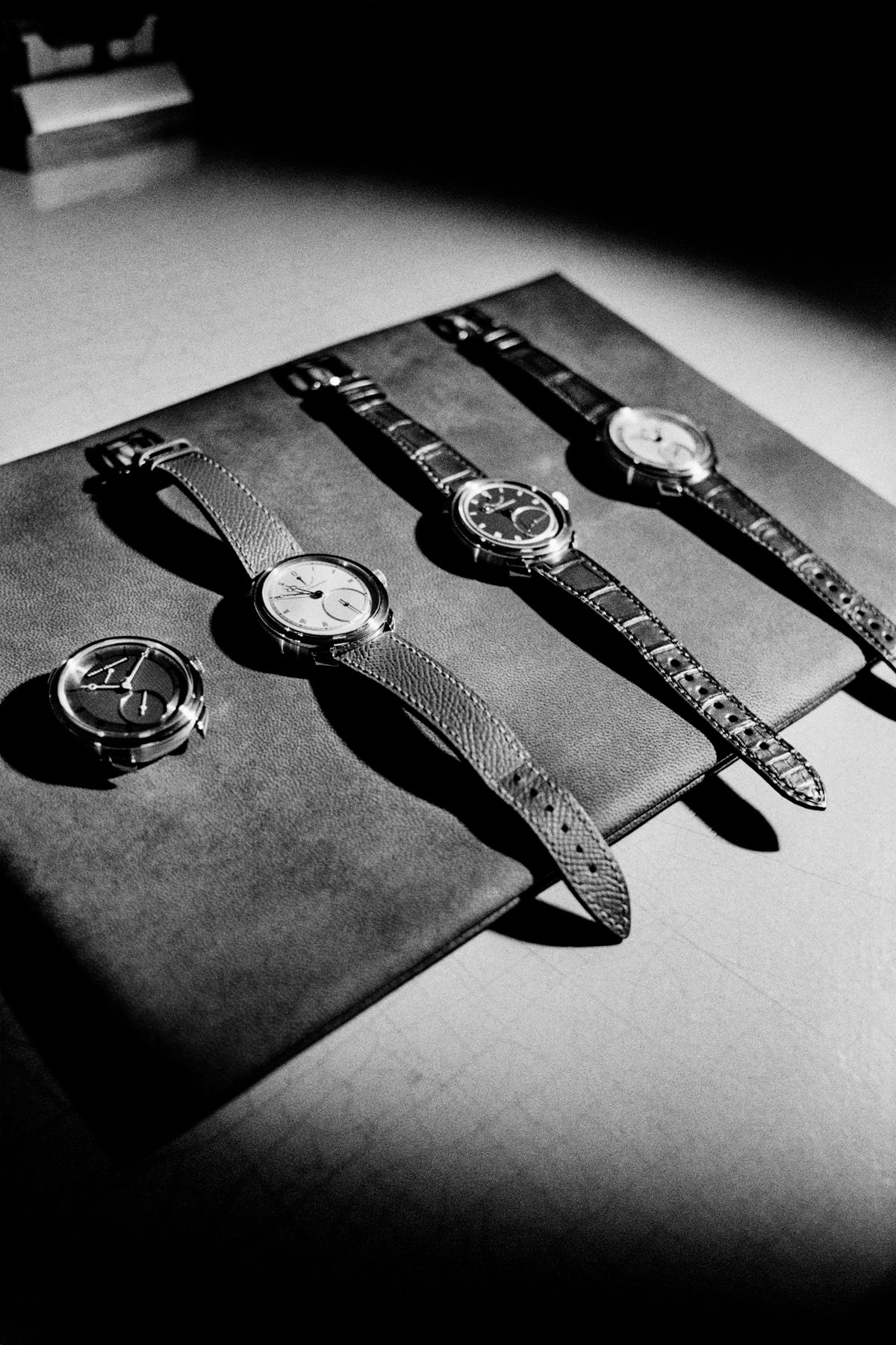A black-and-white photo of four Urban Jürgensen wristwatches arranged on a leather mat