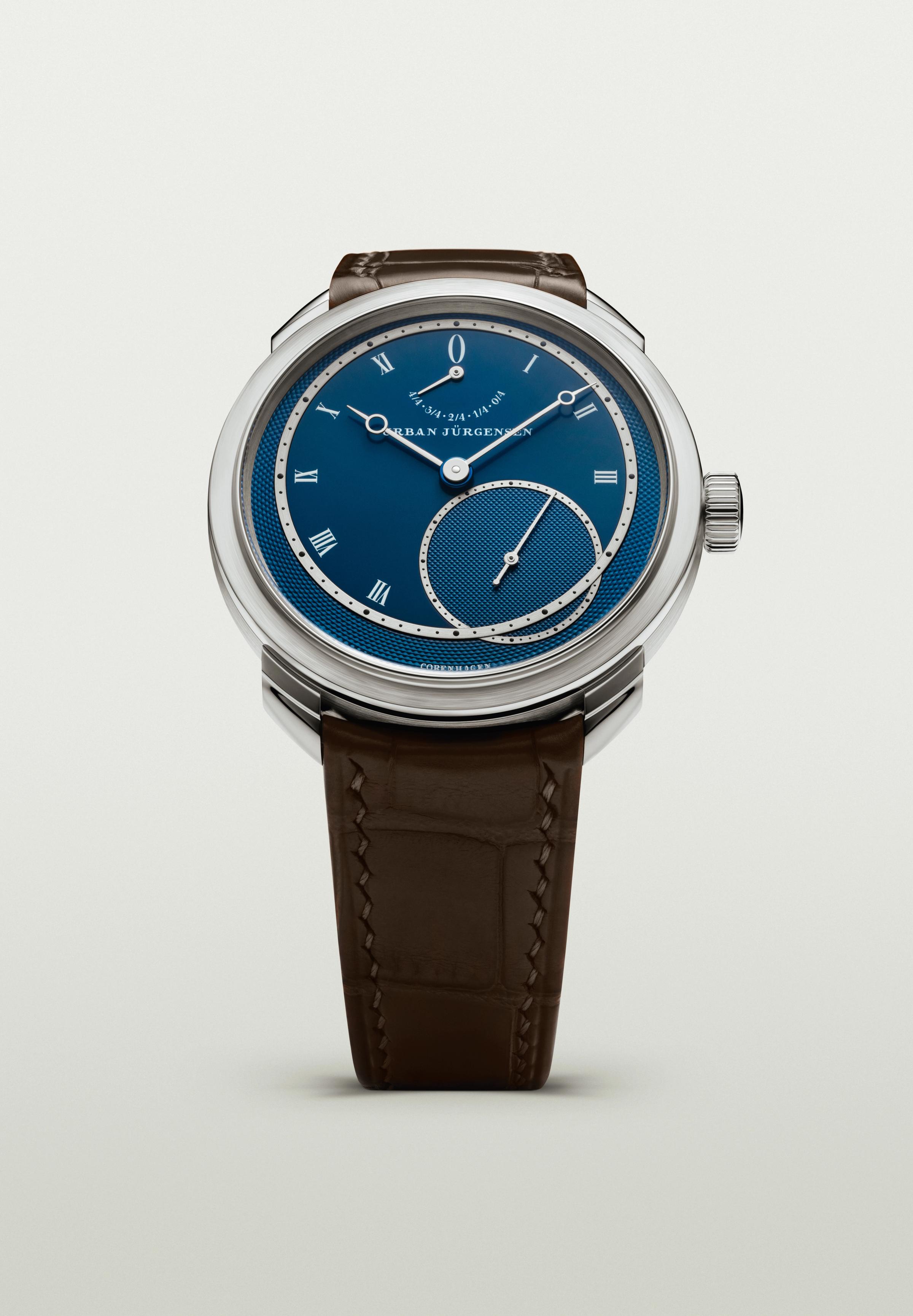 Platinum Urban Jürgensen wristwatch with blue guilloché dial, silver Roman numerals, power reserve indicator, and brown leather strap.
