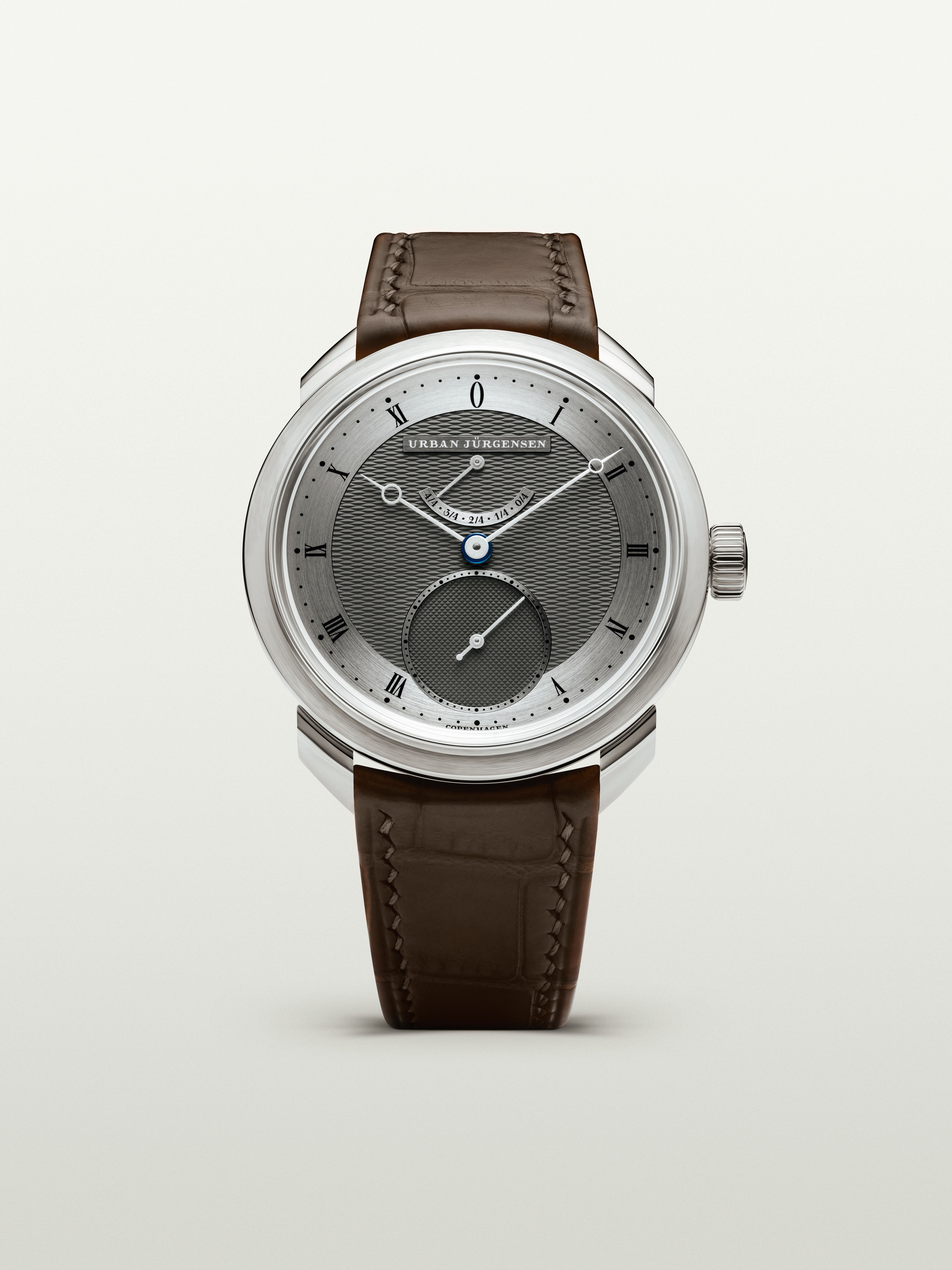 Urban Jürgensen wristwatch with a two-tone guilloché dial, Roman numerals, blued hands, and a brown leather strap.
