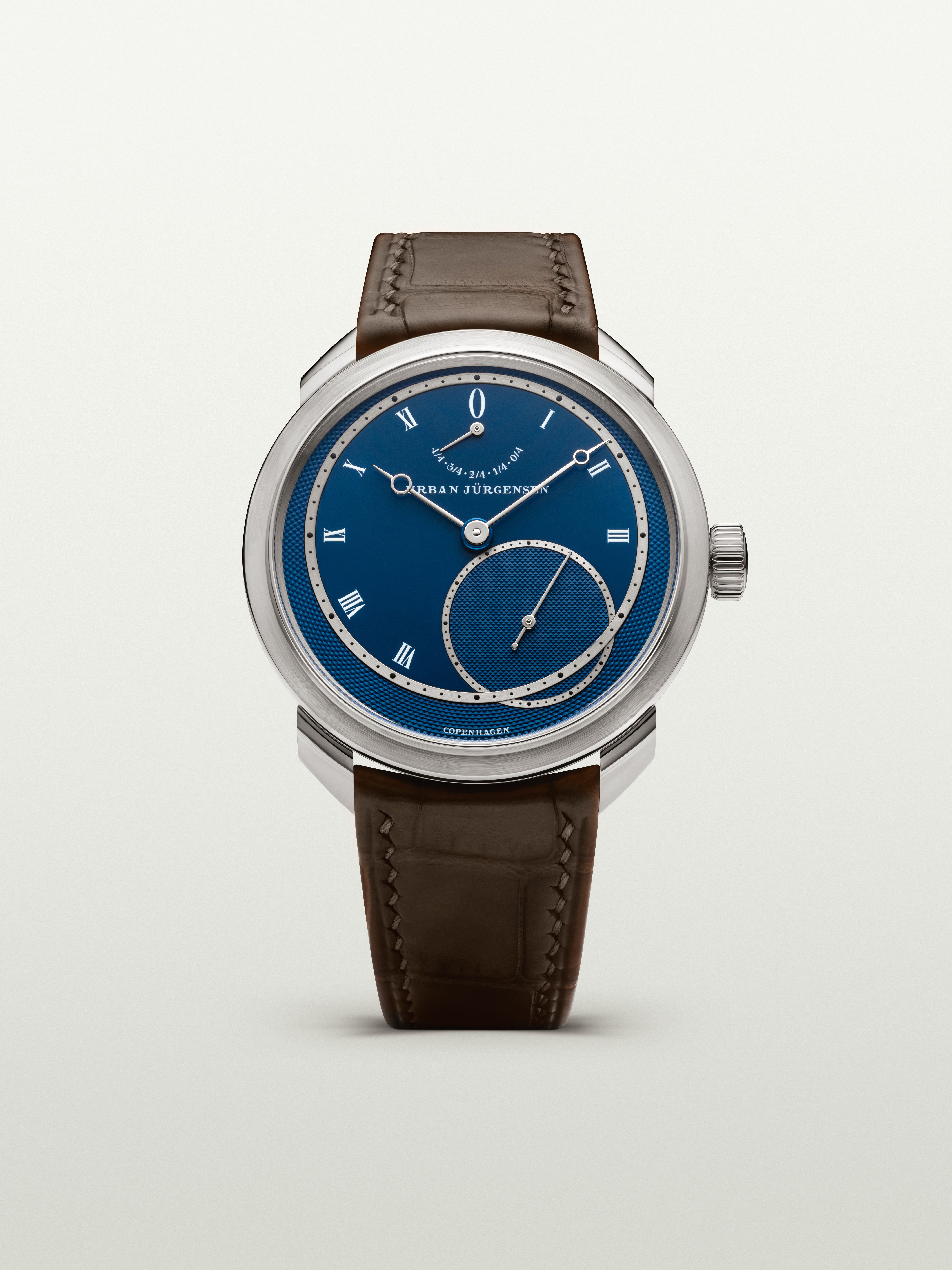 Platinum Urban Jürgensen wristwatch with blue guilloché dial, silver Roman numerals, power reserve indicator, and brown leather strap.