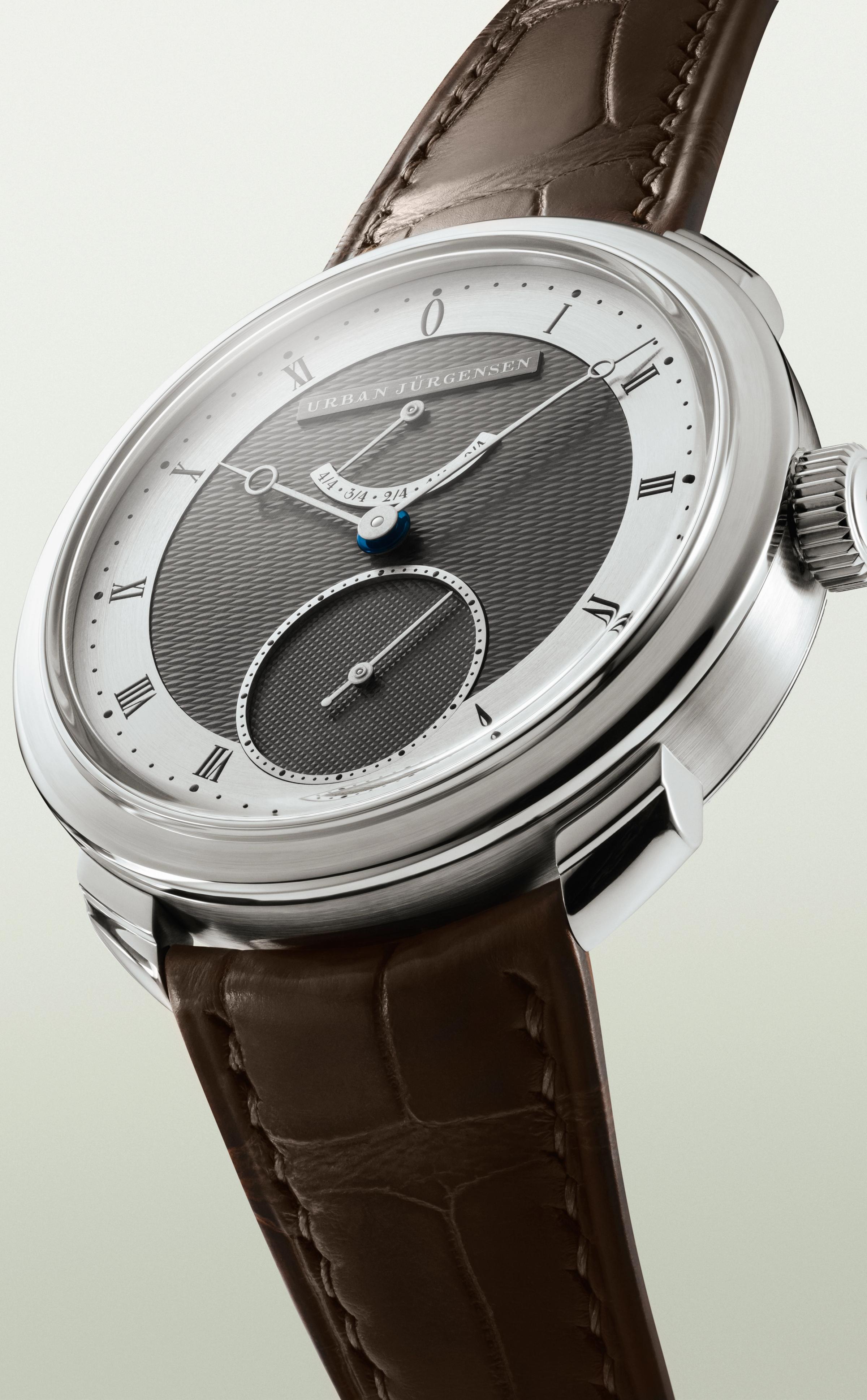 Urban Jürgensen wristwatch with a two-tone guilloché dial, Roman numerals, blued hands, and a brown leather strap.