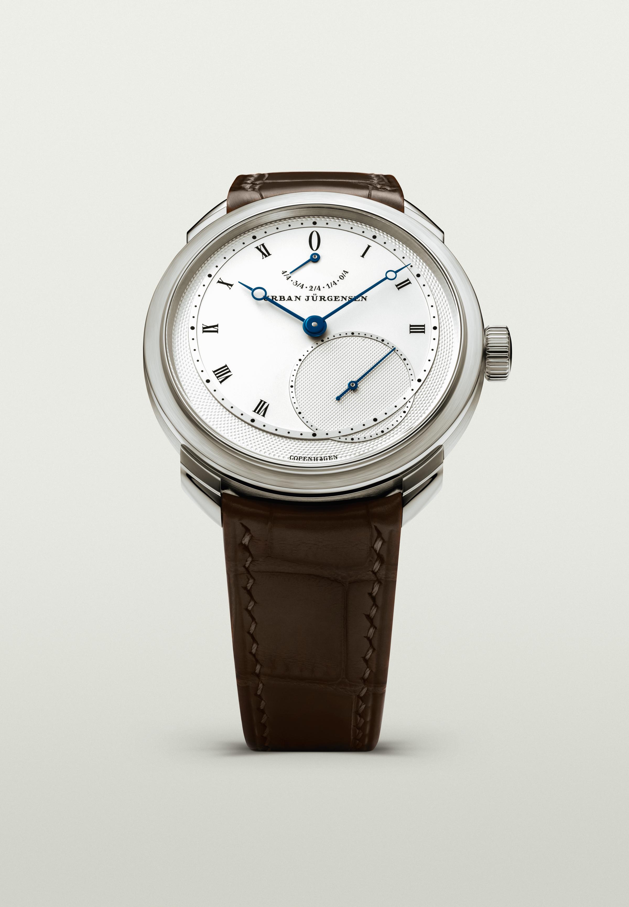 Platinum Urban Jürgensen wristwatch with silver dial, blued hands, Roman numerals, power reserve indicator, and brown leather strap.